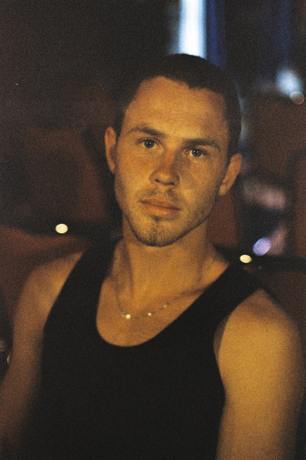 Close portrait of Henry West in a black singlet, warm light, looking at the camera.